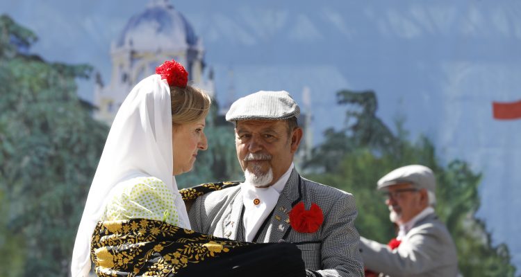 Pareja de chulapos bailando con el cartel detrás